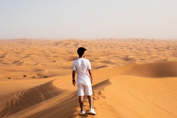 A lone traveler explores the expansive sand dunes of Dubai, capturing the essence of desert adventure.