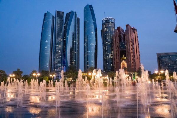 View of Abu Dhabi's skyline with illuminated fountains at twilight, showcasing modern architecture.