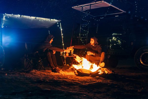 Campers gather around a warm bonfire under a starry sky, enjoying an outdoor adventure near Mashhad, Iran.